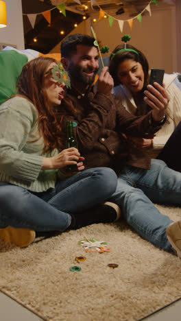 Vertical-Video-Of-Friends-Dressing-Up-At-Home-Celebrating-At-St-Patrick's-Day-Party-Making-Video-Call-On-Mobile-Phone-2